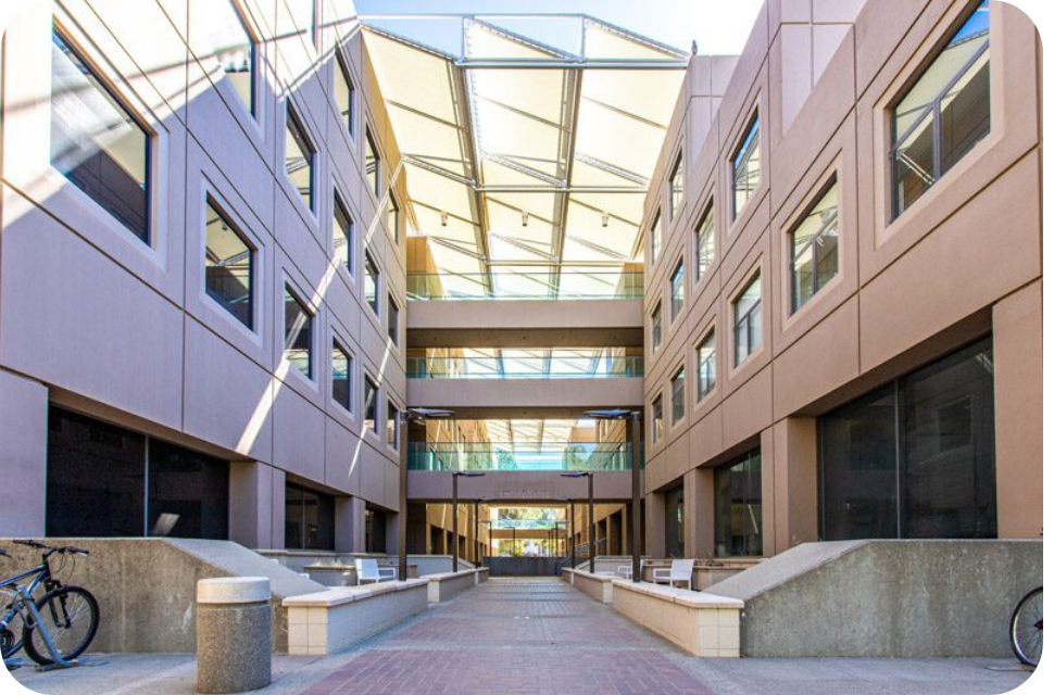 Sunlit atrium between modern office buildings with glass skylight and elevated walkways