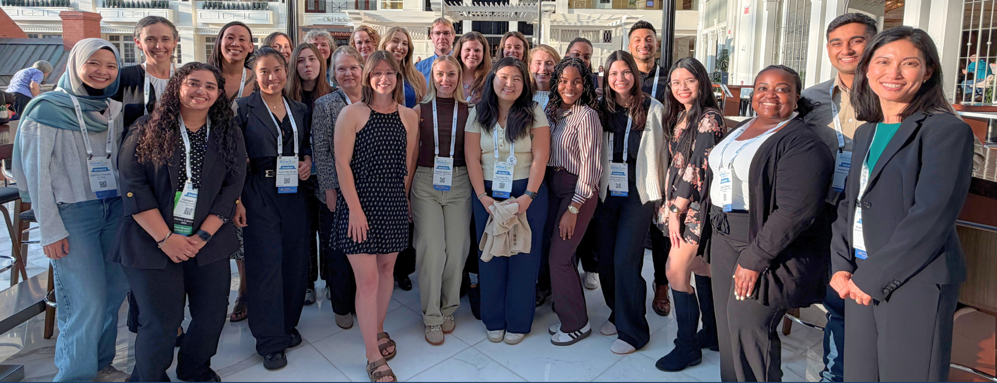 Diverse conference attendees posing on outdoor terrace, smiling, group photo