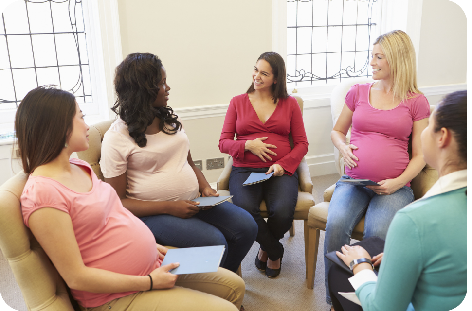 Six pregnant women sitting in a bright circle, smiling and talking