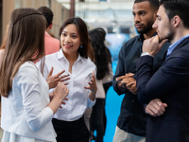 Small group of business professionals conversing on a blue-carpeted conference aisle