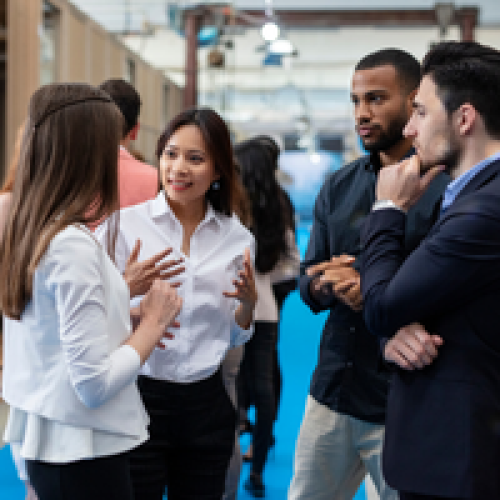 Small group of business professionals conversing on a blue-carpeted conference aisle