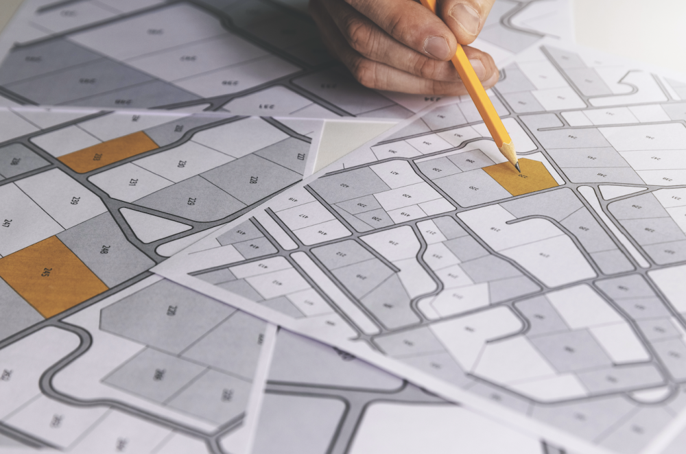 Hand marking a printed property map with pencil; some parcels shaded yellow