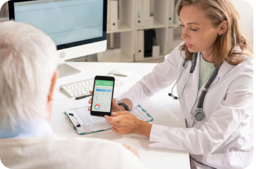 Doctor showing senior patient a health app on a smartphone at a clinic desk