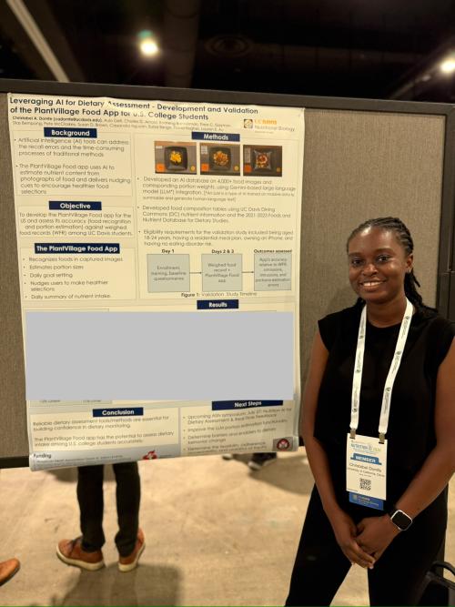 Smiling woman in black sleeveless top poses by a research poster at a conference
