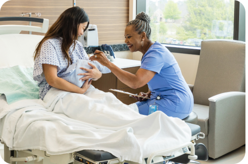 Nurse in blue scrubs helps smiling mother hold newborn — photo