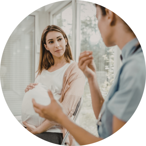 Pregnant woman attentively listening to a clinician in a bright clinic setting