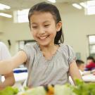 Two kids, one grabbing for fruits