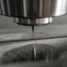 Close-up of precision drill bit touching steel workpiece with ruler marks