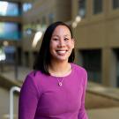 Smiling woman in purple top, professional headshot in modern atrium