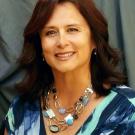 Studio portrait of smiling woman in blue patterned dress and turquoise necklace