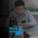 Three students studying at a table outdoors; woman writing; small blue logo left (photo)